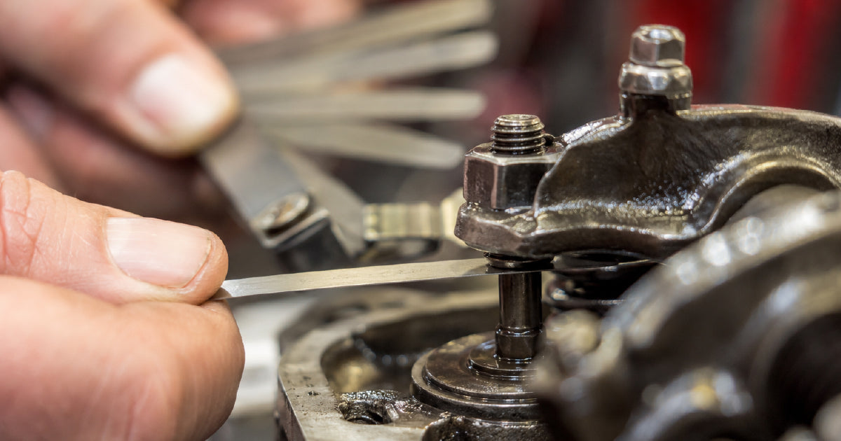 Steel blade feeler gauge being used to measure valve clearance gap showing correct drag technique for metric and imperial measurement guide Australia