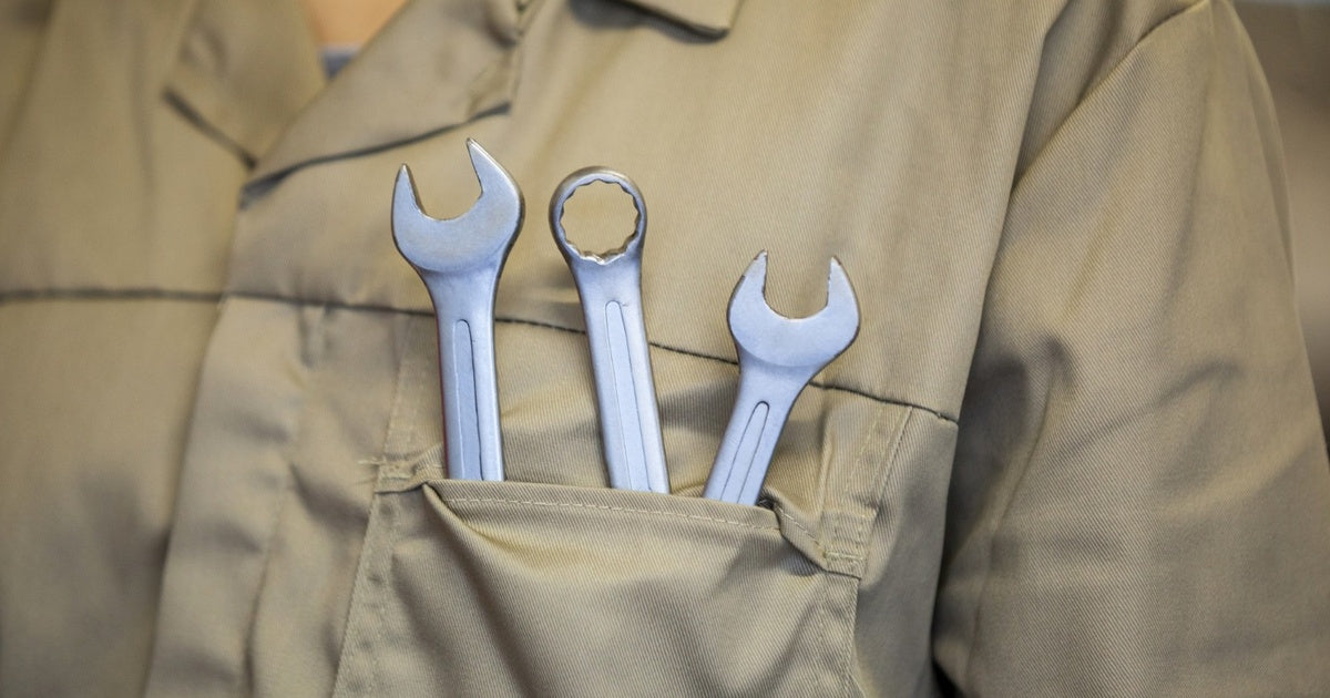 Three types of spanners stored in a tradesperson's chest pocket — an open-end spanner, a ring spanner and a combination spanner in chrome-vanadium finish tucked into a khaki work shirt