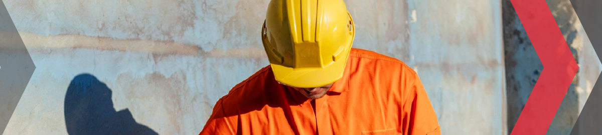 Construction worker in an orange hi-vis shirt and yellow hard hat on a job site.