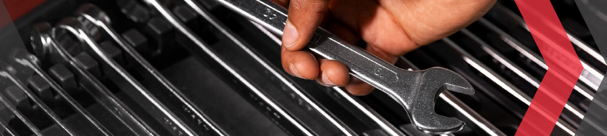 Hand selecting a spanner from an organised set of chrome spanners in a tool tray