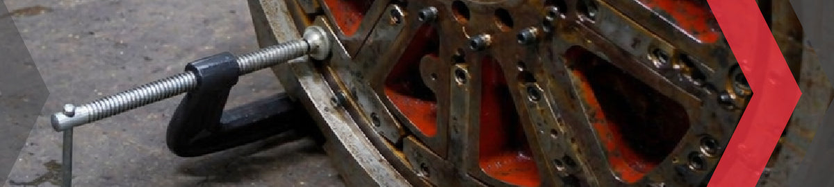 C-clamp securing a heavy-duty industrial wheel or machinery component on a workshop floor