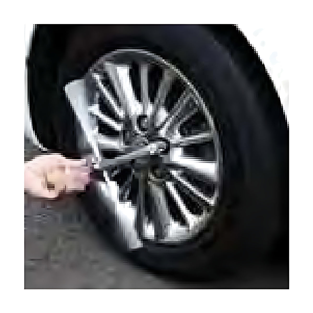 Hand turning a cross wrench on a car wheel nut, with the alloy wheel and tyre visible