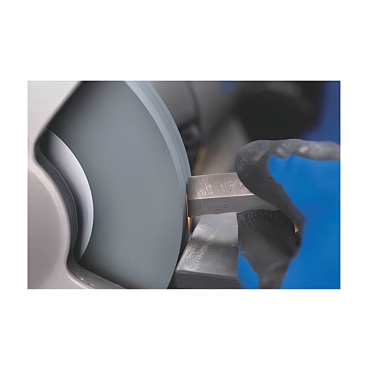 Pferd Bench Grinding Wheel Silicon Carbide (Carbide, gloved hand holding a rectangular steel tool against a grey bench grinding wheel, sparks at the contact point