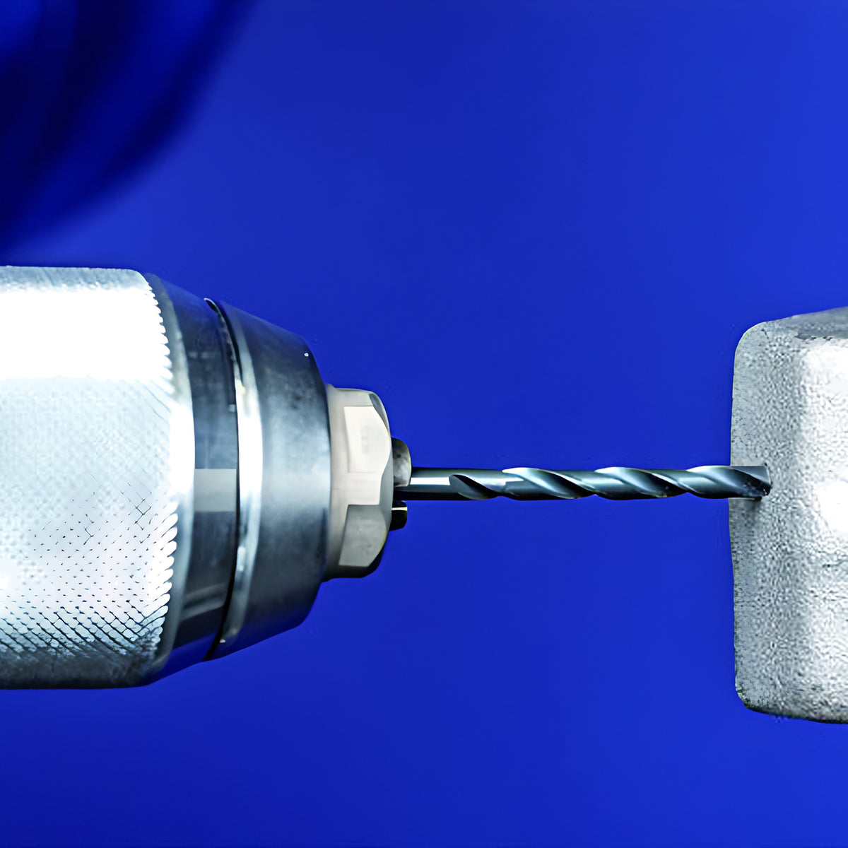 Pferd twist drill in a hand drill chuck against a grey metal block, blue background, 8-piece 3 to 8 mm set