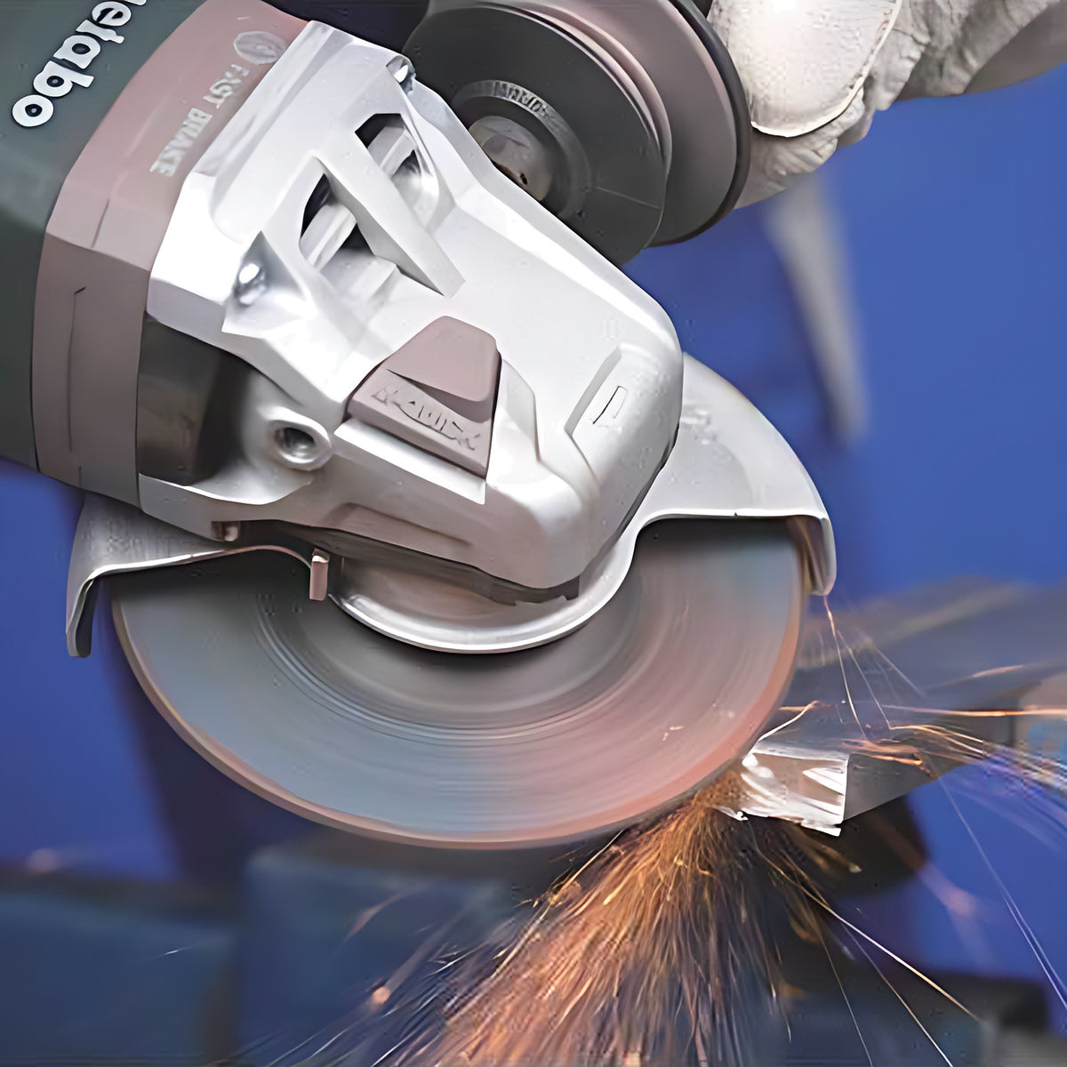 Pferd Duo Steelox wheel on a grey angle grinder, cutting a steel block held in a blue vice, orange sparks