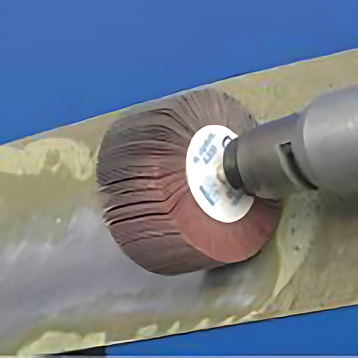 Pferd fan grinder 80 x 40 mm on a grinder working along a long olive and grey metal beam, blue background