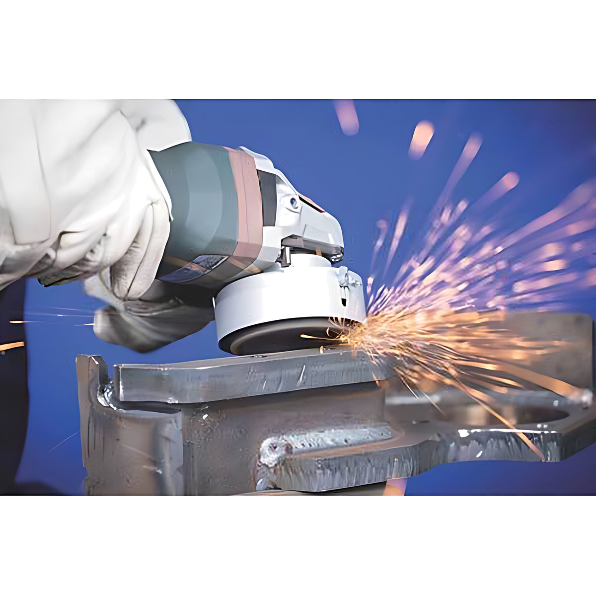 Pferd SG STEELOX cup wheel work shot, gloved operator grinding a clamped steel workpiece with an angle grinder, sparks flying
