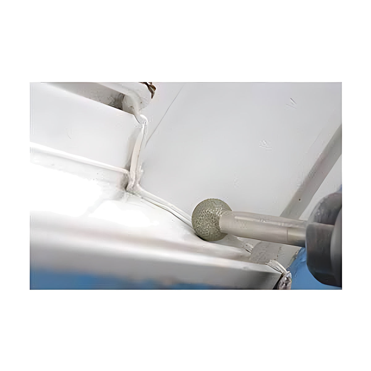 Pferd KU ball shape diamond grinding point in a hand-held grinder, working on the weld area of a white metal edge