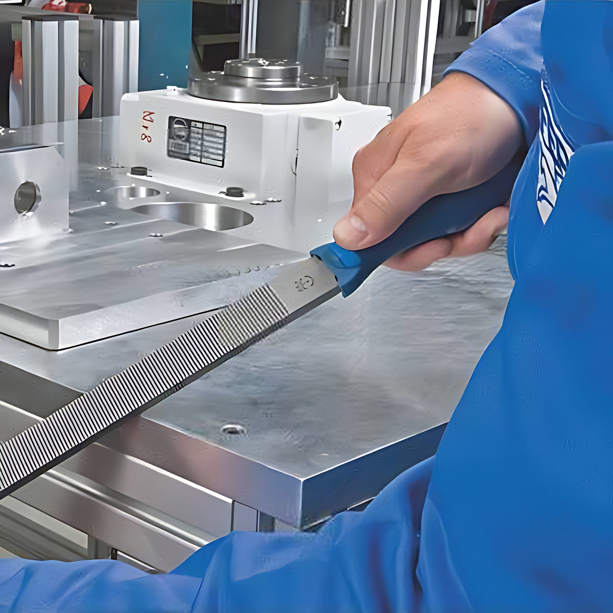 Pferd lathe file 1612 DE in use, worker in blue filing an aluminium plate on a machined bench