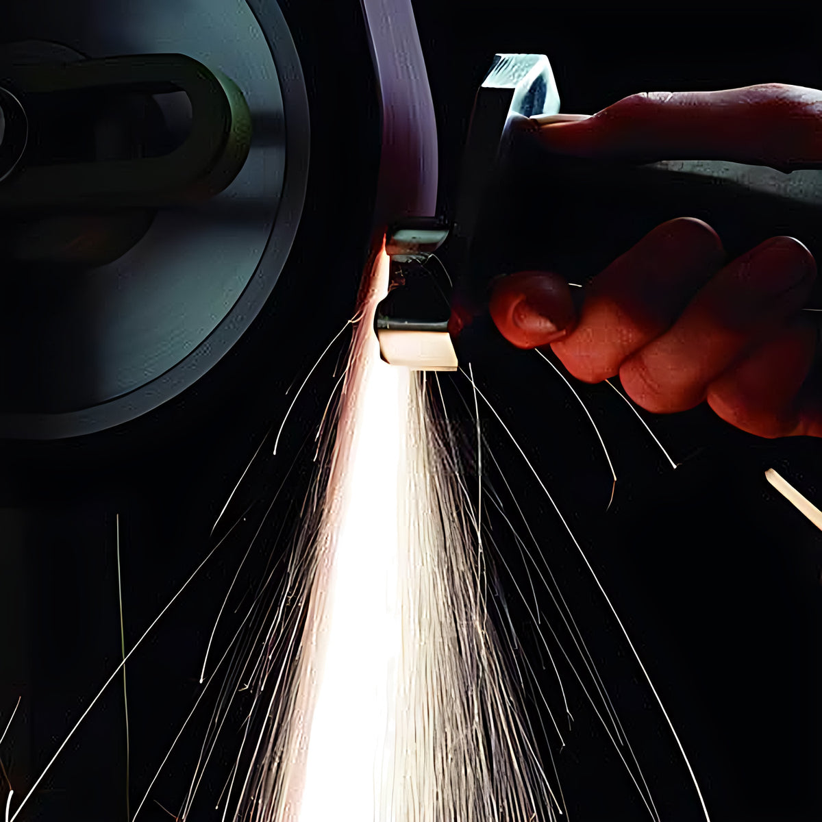 Pferd maroon linishing belt 50 x 914 mm grinding a hand-held part, spark stream on a dark background