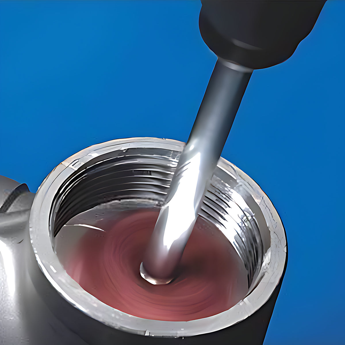 Pferd POLINOX PNST cross buff in use, a spinning pink-red buff on a grey shaft cleaning inside a threaded metal pipe fitting