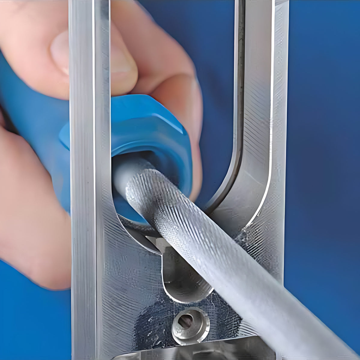Pferd 1162 round file in use, hand holding it with a blue handle inside a slotted metal frame, blue background